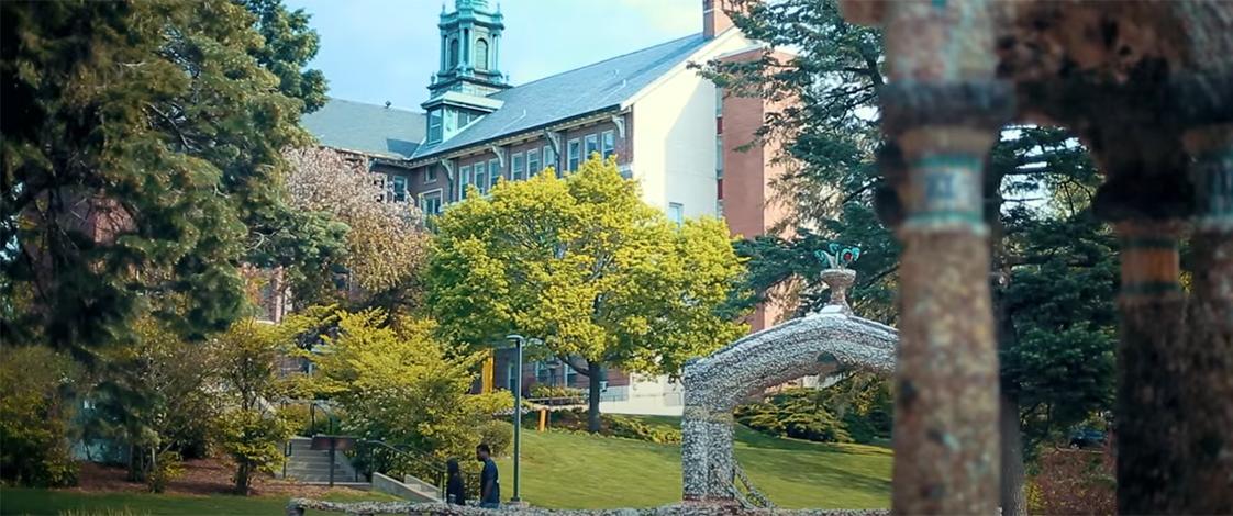 Two students walking through the grotto in front of Warde Hall